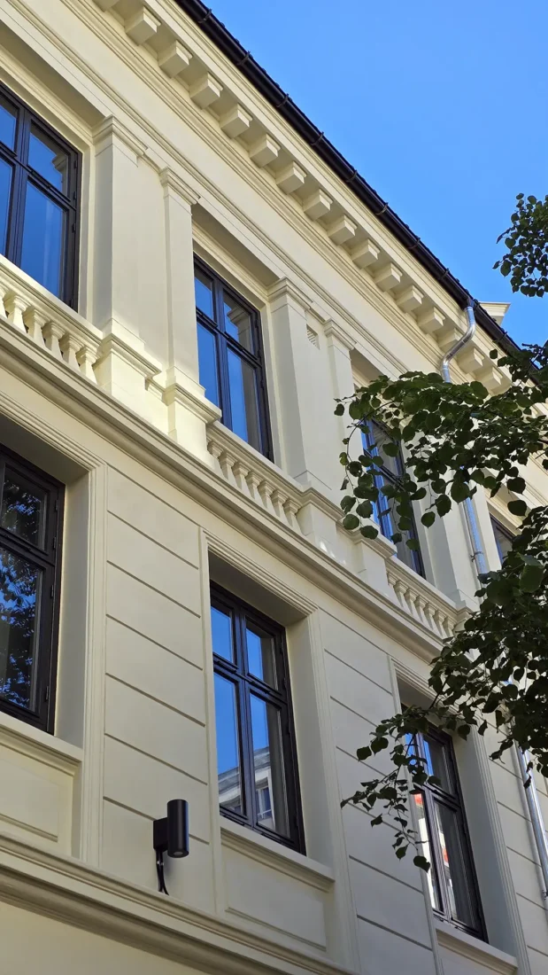 Bygget i Dronningens gate 8 B i Oslo ferdig rehabilitert. Lyst pusset fasade med mørke vindusrammer